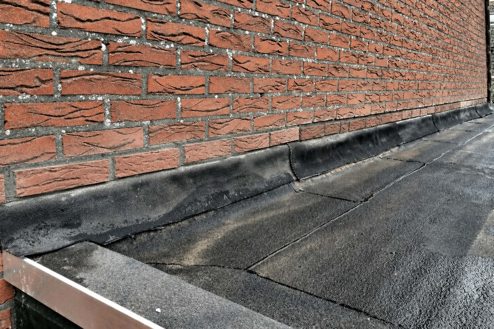 Loodvervanger als waterkering tussen bakstenen gevel en plat EPDM-dak